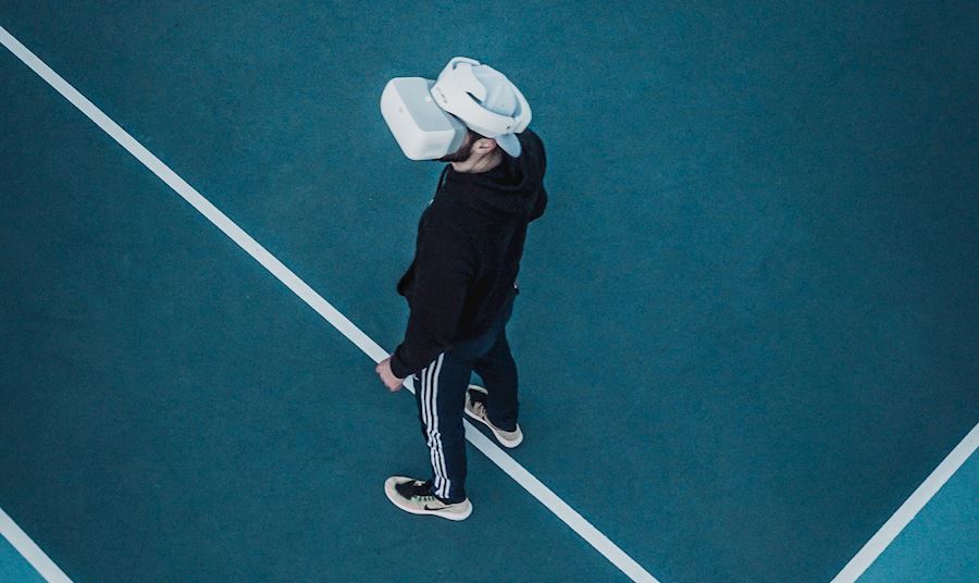 Man standing on tennis court wearing a VR headset